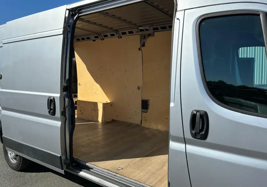Vue latérale droite d’un Peugeot Boxer gris 2019 avec porte coulissante ouverte montrant l’intérieur en bois clair.