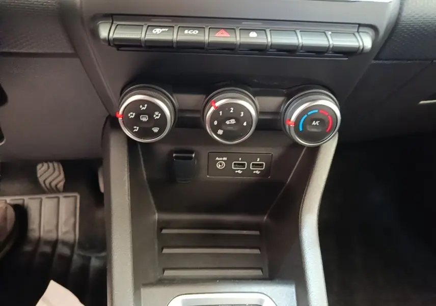 Gros plan sur les commandes de climatisation et ports USB de la Renault Clio Business TCe 90 blanche, intérieur noir.