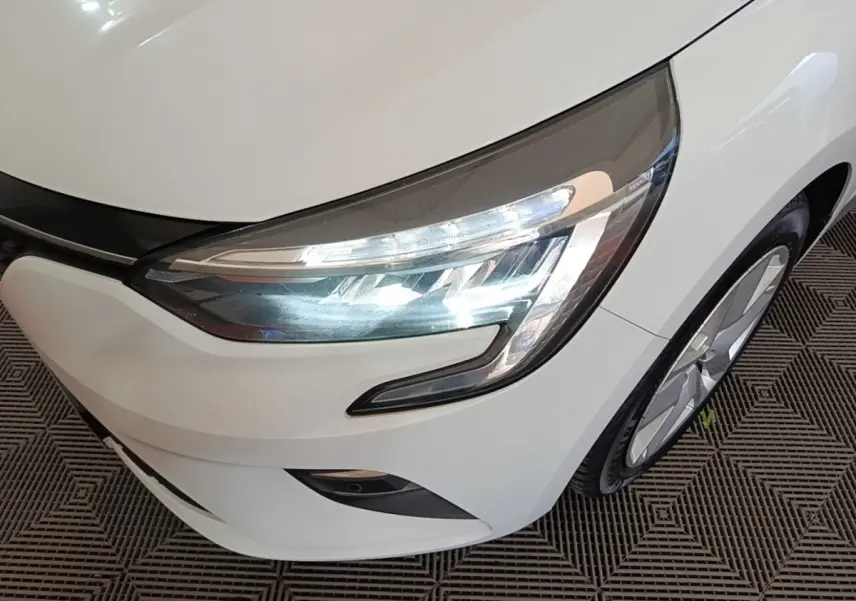 Gros plan sur l'avant droit blanc d'une Renault Clio 2020, mettant en valeur le phare LED et la roue.