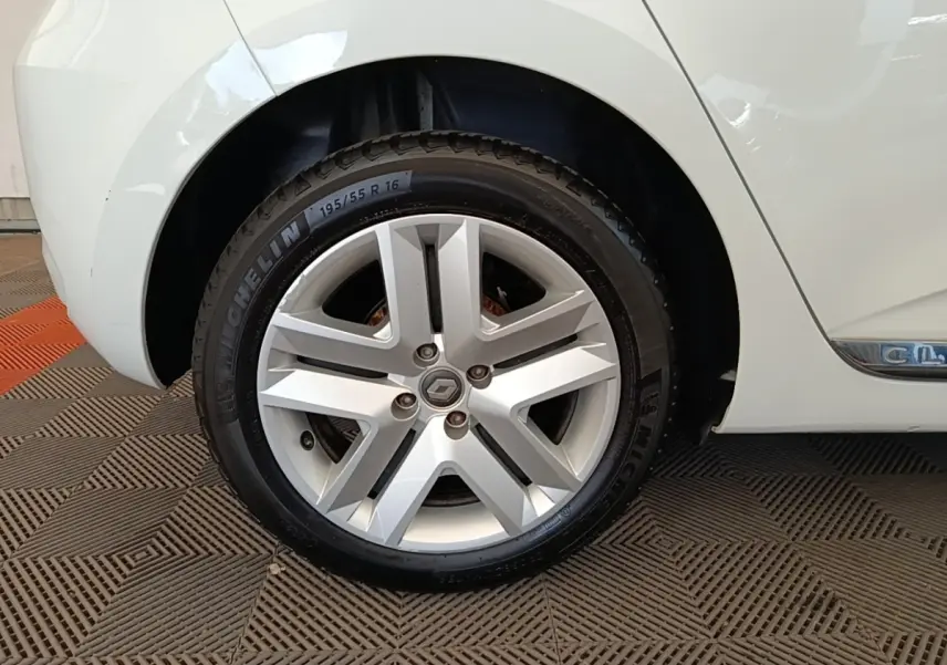 Gros plan sur la roue arrière droite d’une Renault Clio blanche, avec jante alliage et logo Renault central.