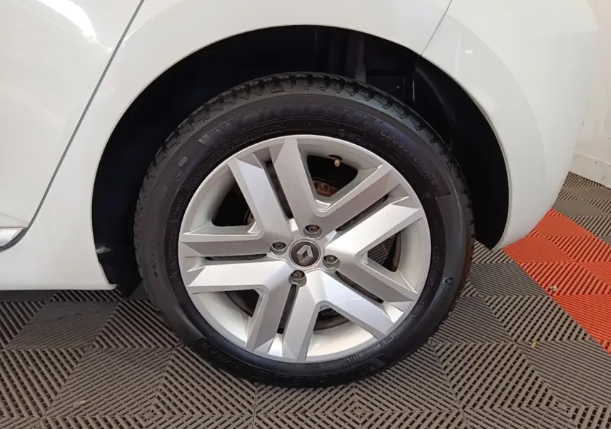 Gros plan sur la roue avant gauche d'une Renault Clio blanche, avec jante alliage et logo Renault central.