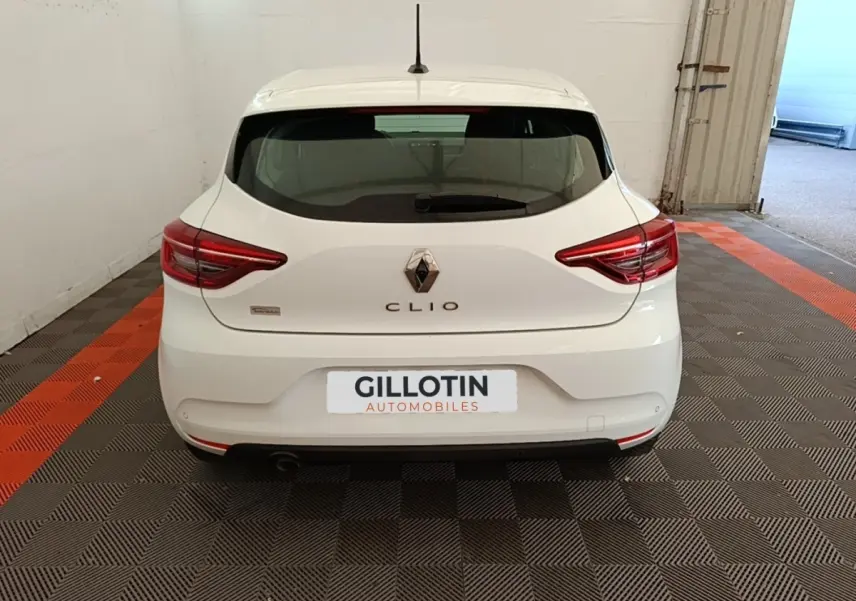 Vue arrière d'une Renault Clio blanche 2020, avec feux LED et logo distinctif sur un sol à motifs gris et orange.