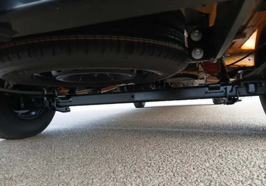 Vue en contre-plongée sous un Renault Master orange 2026, montrant la roue de secours et le châssis arrière.