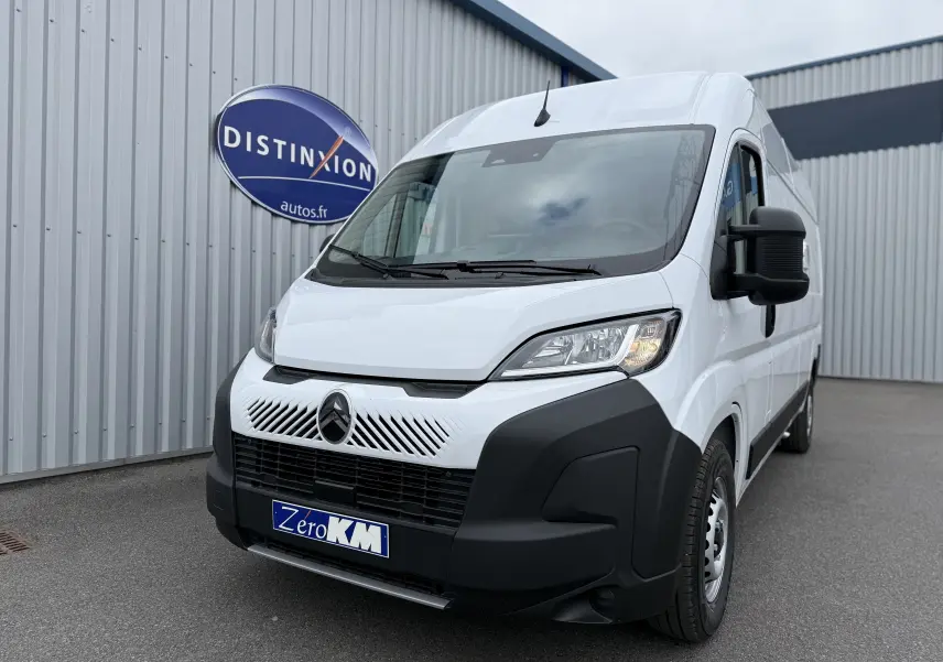 Vue 3/4 avant d’un Citroën Jumper L3H2 blanc avec calandre noire et logo distinctif devant un bâtiment industriel.