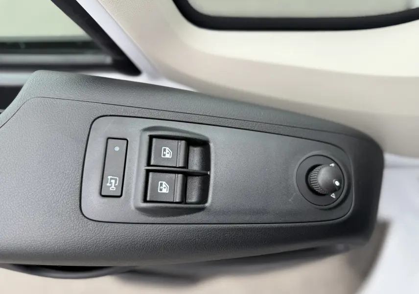 Gros plan sur les commandes noires des vitres et rétroviseurs côté gauche d'un Citroën Jumper blanc 2025 L3H2.
