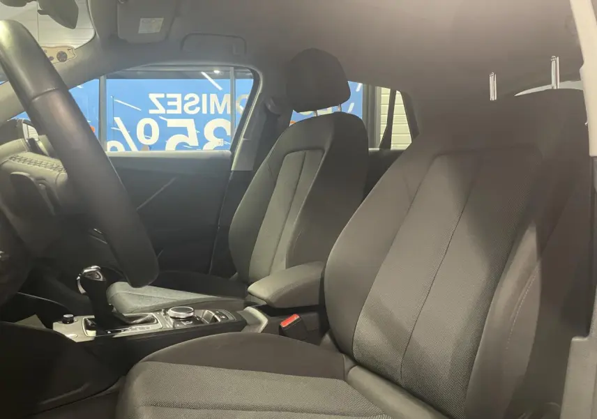 Vue intérieure côté droit des sièges avant en tissu noir de l'Audi Q2 2023 avec console centrale et levier de vitesses.