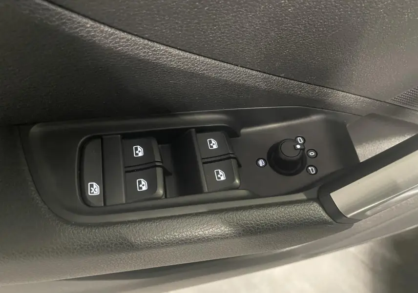 Gros plan sur les commandes de lève-vitres et réglage des rétroviseurs côté conducteur de l'Audi Q2 noir métallisé 2023.