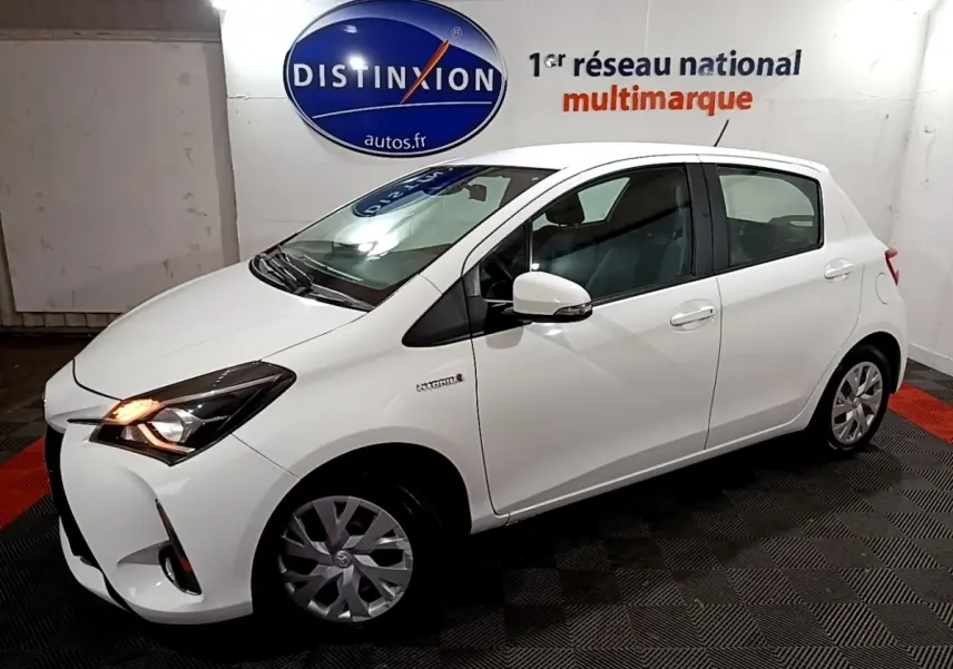 Toyota Yaris hybride blanche vue de profil droit 3/4 avant, avec phares allumés et jantes alliage.