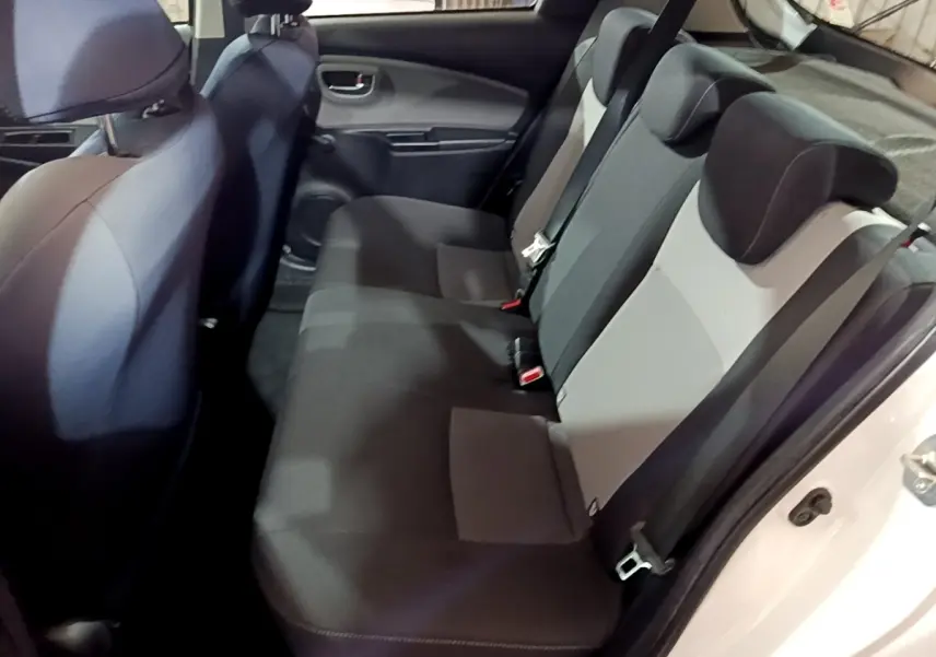 Vue intérieure côté droit montrant la banquette arrière noire et grise de la Toyota Yaris 1.5 Hybrid 2019 blanche.