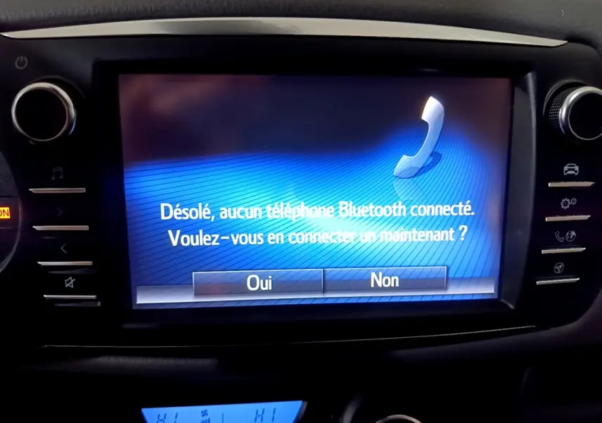Écran tactile central de la Toyota Yaris hybride 2019 affichant un message Bluetooth, entouré de commandes noires.