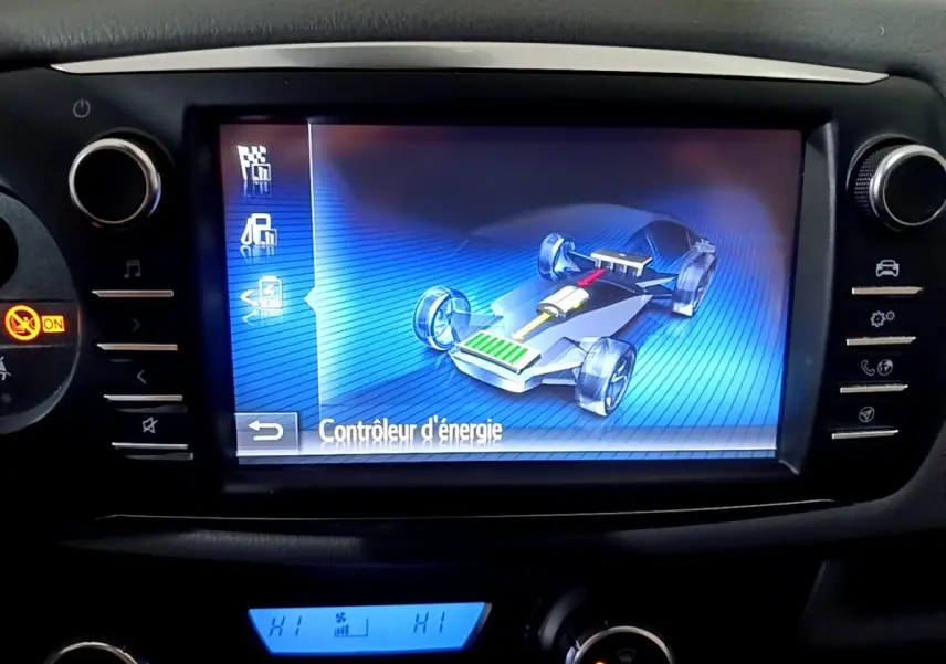 Écran tactile central montrant le contrôle d'énergie hybride sur Toyota Yaris 1.5 VVT-i Hybrid, tableau de bord noir.