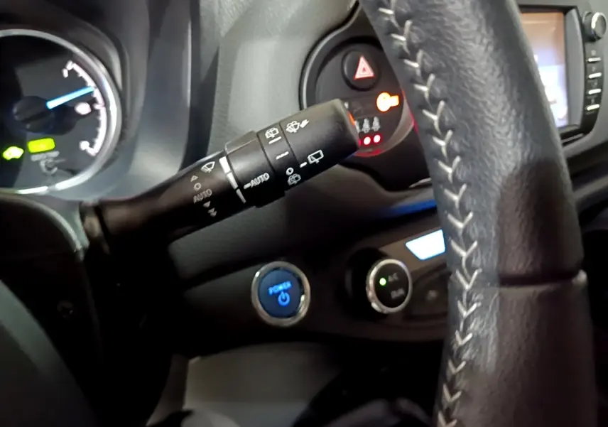 Vue rapprochée de l’intérieur de la Toyota Yaris 2019, volant cuir avec commandes, bouton démarrage bleu et tableau de bord partiel.