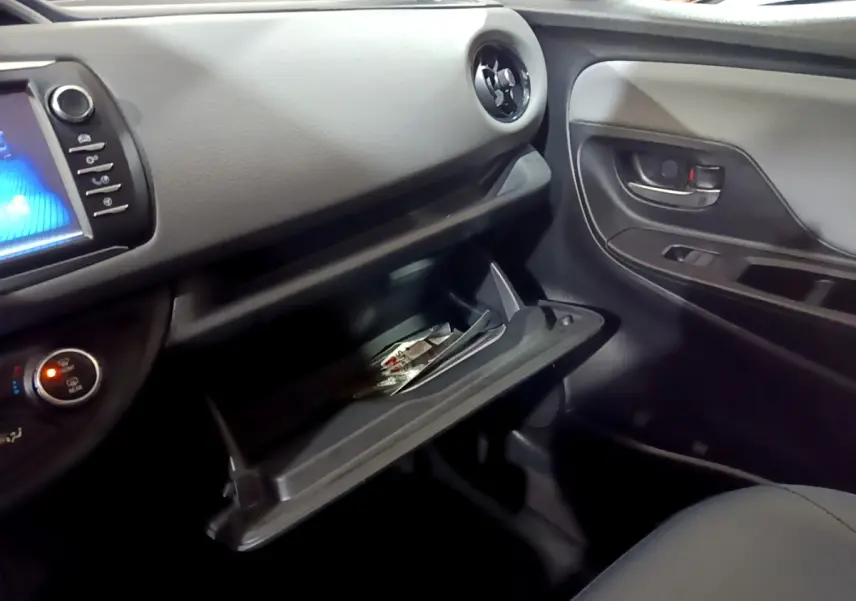 Vue intérieure côté passager de la Toyota Yaris blanche 2019, boîte à gants ouverte avec documents visibles.