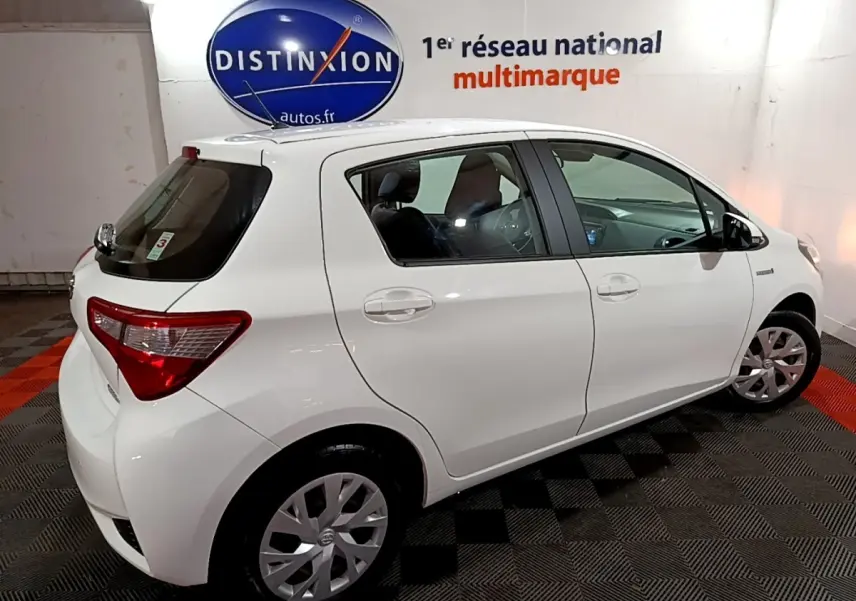 Vue 3/4 arrière droite d'une Toyota Yaris blanche 2019 hybride, avec jantes alliage et vitres teintées.