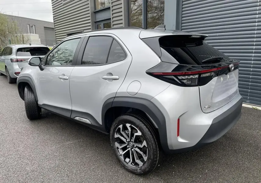 Vue 3/4 arrière droite d'une Toyota Yaris Cross gris clair avec jantes alliage et feux arrière LED noirs.