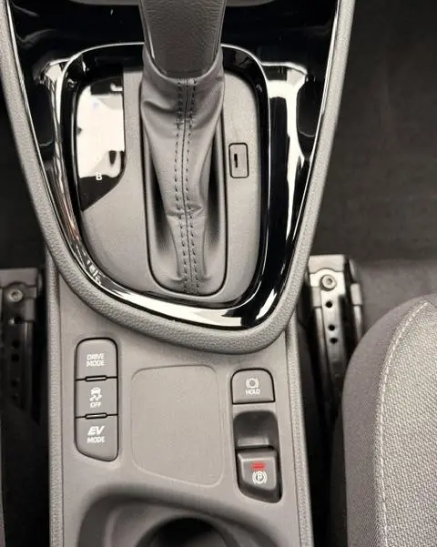 Gros plan sur la console centrale noire de la Toyota Yaris Cross 1.5 Hybrid, avec levier de vitesse automatique et boutons de contrôle.