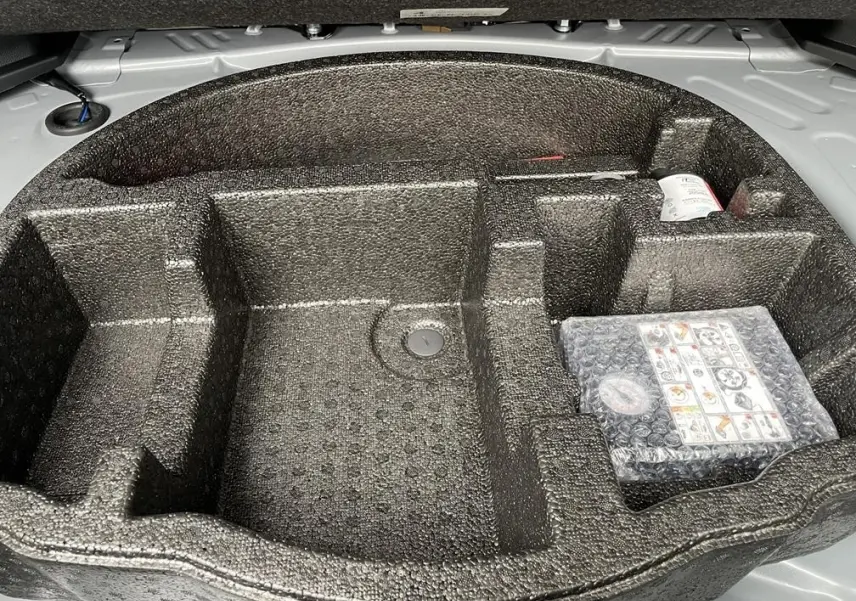 Vue rapprochée du compartiment de rangement en mousse noire dans le coffre de la Toyota Yaris Cross gris clair.