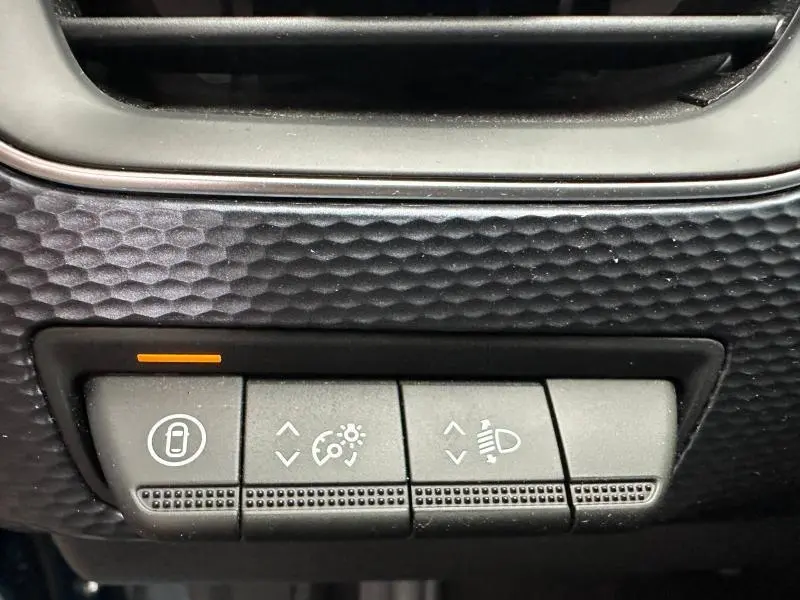 Détail des commandes d’éclairage et verrouillage sur tableau de bord noir texturé du Renault Arkana Bleu Zanzibar 2025.
