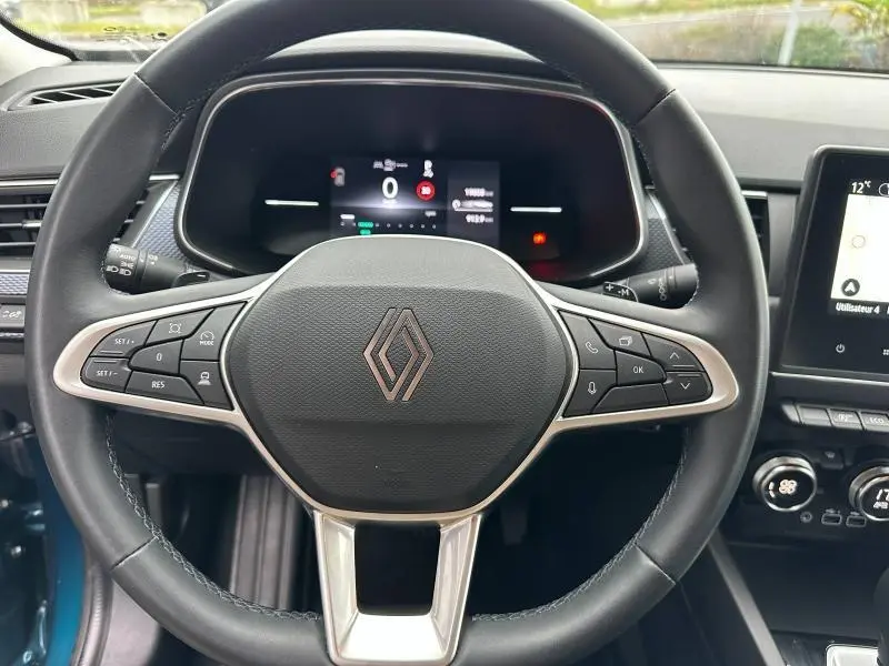 Vue rapprochée du volant multifonction noir du Renault Arkana 2025, avec tableau de bord numérique en arrière-plan.