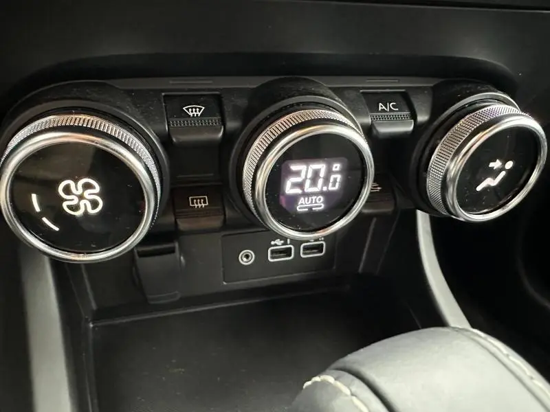 Gros plan sur les commandes de climatisation du Renault Arkana 2025, avec affichage digital à 20°C et boutons ronds chromés.