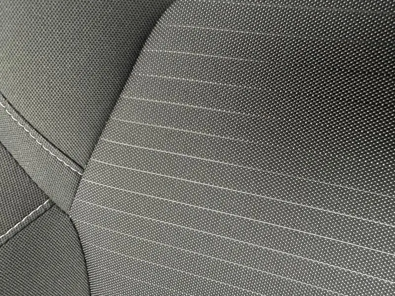 Détail du tissu gris à motifs rayés et coutures blanches sur la sellerie d’un Renault Arkana 2025.