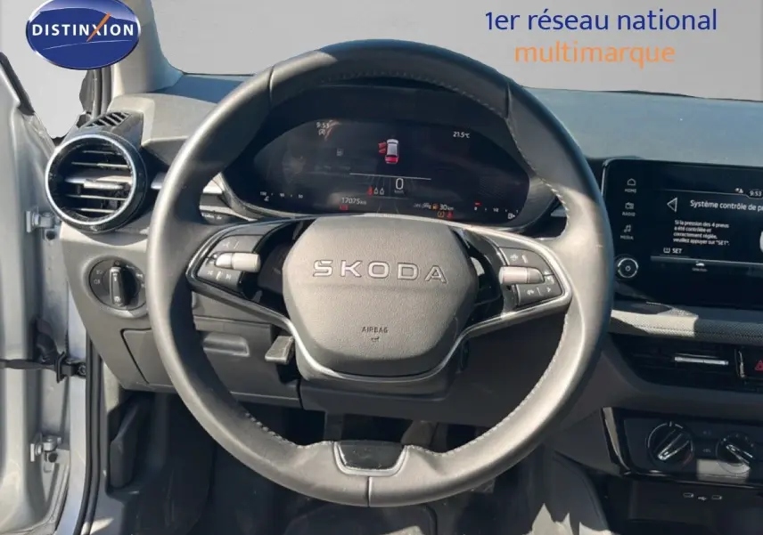 Vue intérieure centrée sur le volant SKODA d’une Fabia 2025 gris argent avec tableau de bord numérique et écran tactile.