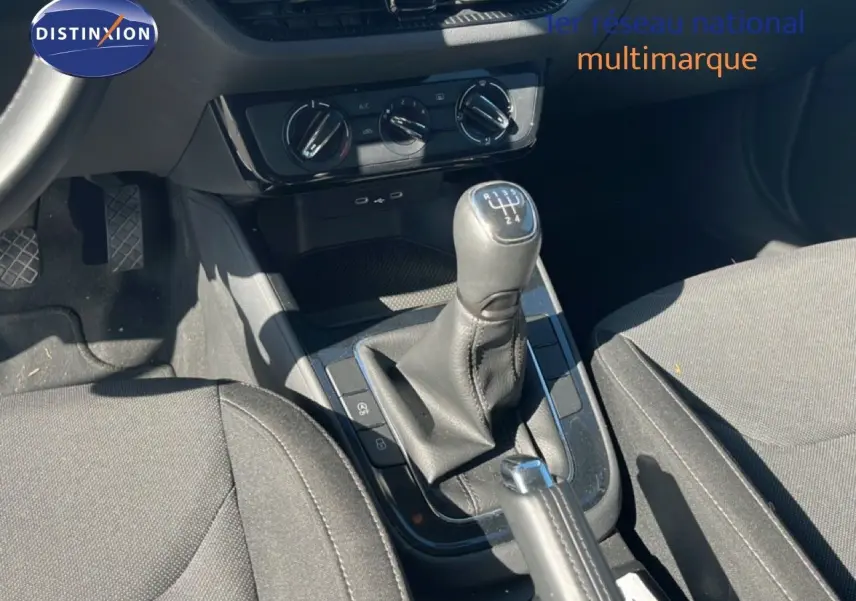 Vue intérieure centrée sur la console centrale et levier de vitesse manuel d'une Skoda Fabia 2025 en tissu gris.
