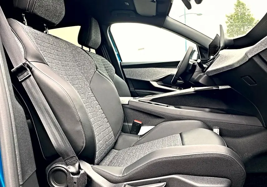 Vue intérieure côté conducteur du Peugeot 3008 2025 bleu, sièges tissu et cuir gris avec console centrale moderne.