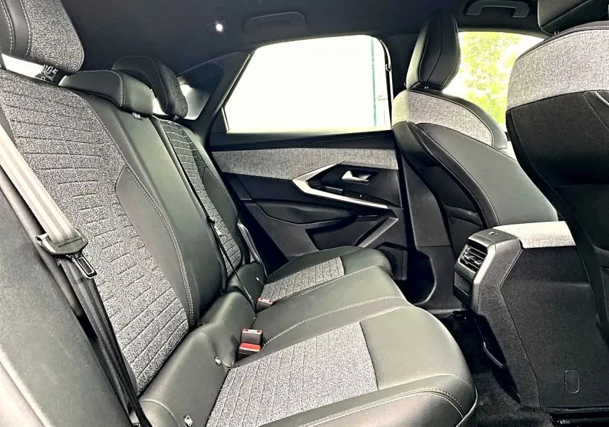 Vue intérieure arrière côté droit du Peugeot 3008 2025, sièges bi-matière gris et noir avec coutures contrastées.