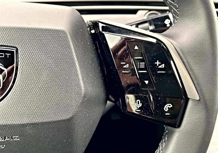 Gros plan sur le côté droit du volant cuir du Peugeot 3008 bleu 2025 avec commandes audio et téléphone intégrées.
