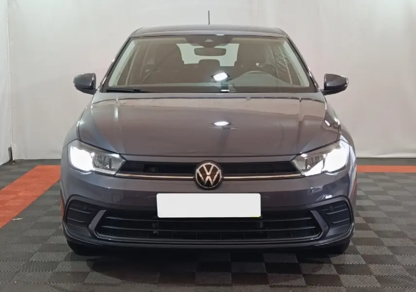 Vue frontale d'une Volkswagen Polo gris foncé 2025 avec phares LED allumés dans un studio.