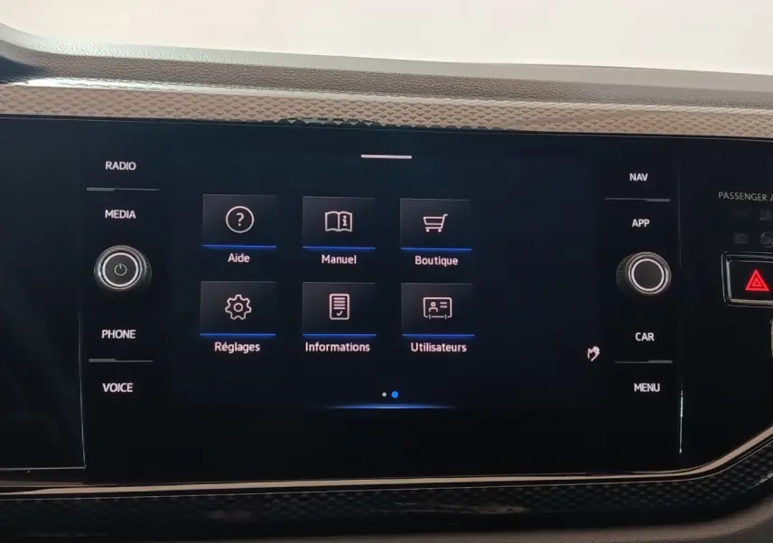 Écran tactile central de la Volkswagen Polo gris foncé, affichant le menu principal avec options d’aide et réglages.