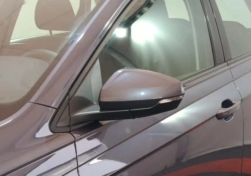 Gros plan sur le rétroviseur côté gauche d'une Volkswagen Polo gris foncé avec poignée de porte visible.