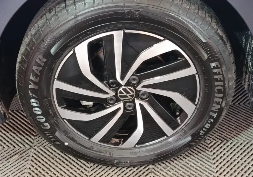 Gros plan sur la jante alliage noire et argentée d'une Volkswagen Polo gris foncé, avec pneu Goodyear visible.
