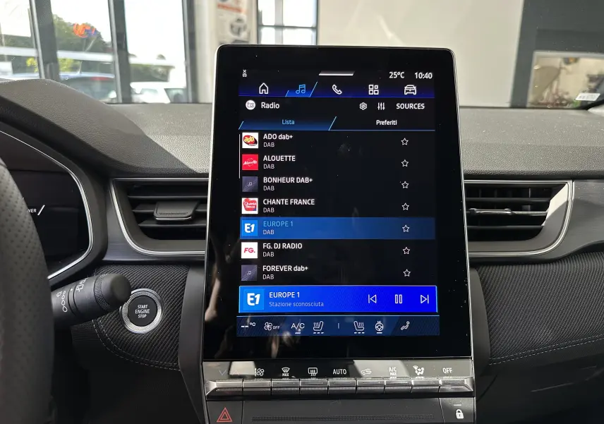 Vue rapprochée de l'écran tactile central du tableau de bord du Renault Symbioz gris Cassiopée, affichant les stations radio DAB.