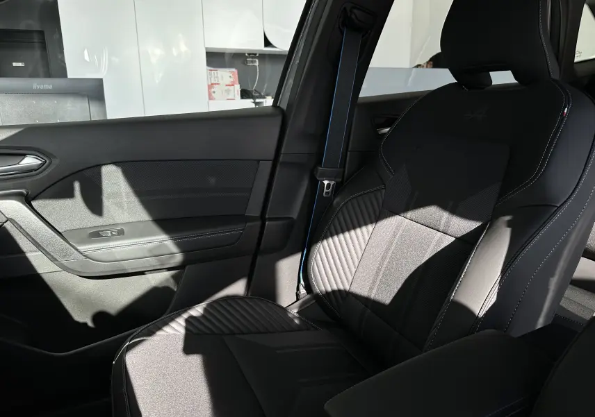 Siège avant droit en cuir noir avec logo Alpine embossé, ceinture de sécurité bleue et panneau de porte intérieur sombre.