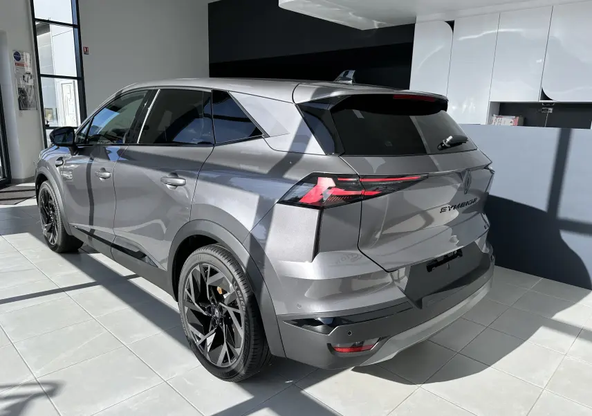 Vue 3/4 arrière droite du Renault SYMBIOZ Esprit Alpine gris Cassiopée avec feux LED et jantes noires en showroom.