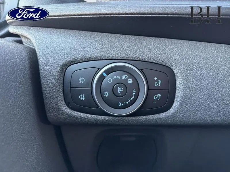 Gros plan sur le bouton de commande des phares noir dans l'habitacle du Ford Transit Custom Fourgon 2023.