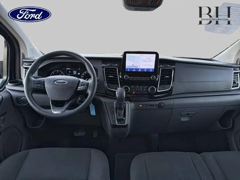 Vue intérieure frontale du tableau de bord du Ford Transit Custom noir, avec écran tactile central et volant multifonctions.