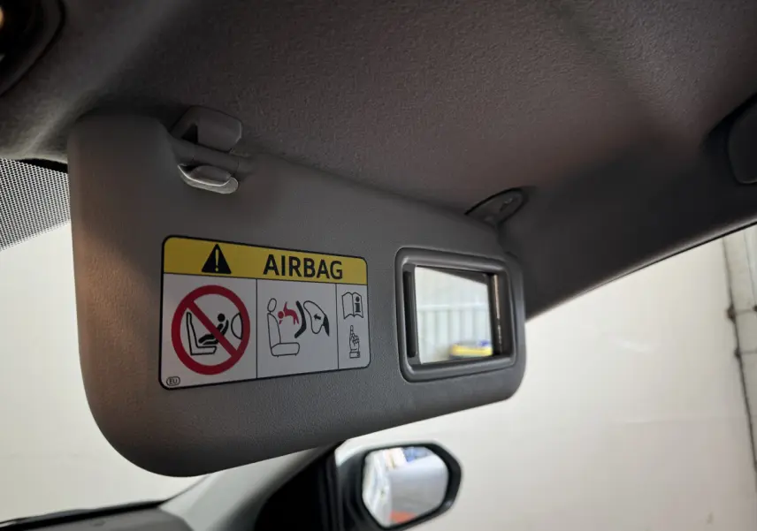 Détail du pare-soleil côté conducteur avec miroir intégré et avertissement airbag dans une Toyota Yaris blanche.