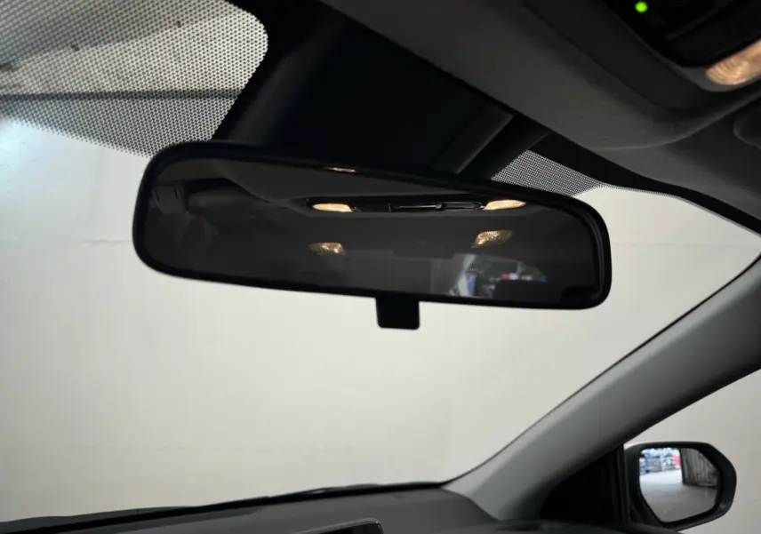 Vue intérieure du rétroviseur central de la Toyota Yaris hybride blanche 2022 avec éclairage intérieur allumé.