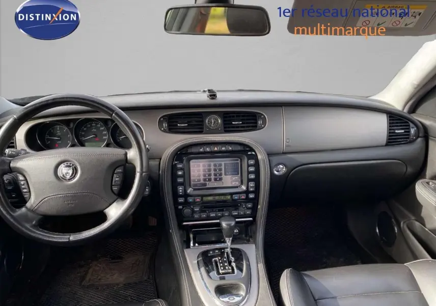 Intérieur de la Jaguar XJ6 2.7 V6 Biturbo 2006 en cuir noir, vue frontale du tableau de bord et console centrale avec écran tactile.