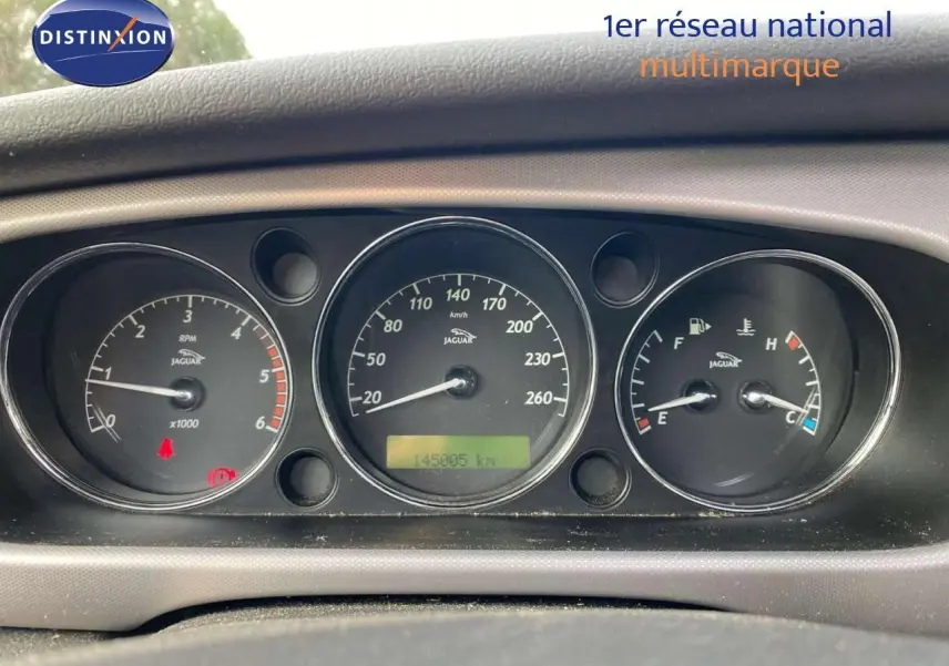 Gros plan sur le tableau de bord noir de la Jaguar XJ6 2.7 V6 Biturbo, affichant compte-tours, vitesse et jauges.
