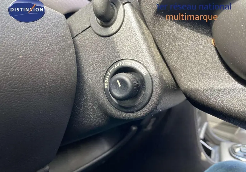 Gros plan sur le bouton de réglage des pédales dans l'habitacle noir d'une Jaguar XJ6 2.7 V6 Biturbo Executive.