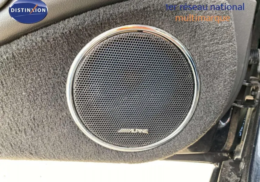 Gros plan sur l'enceinte Alpine intégrée dans la porte côté gauche d'une Jaguar XJ6 noire de 2006.