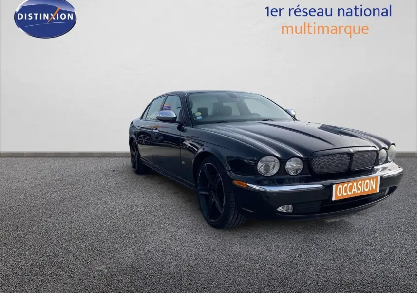 Jaguar XJ6 noir vue 3/4 avant droit, mettant en valeur ses phares ronds et ses jantes noires élégantes.