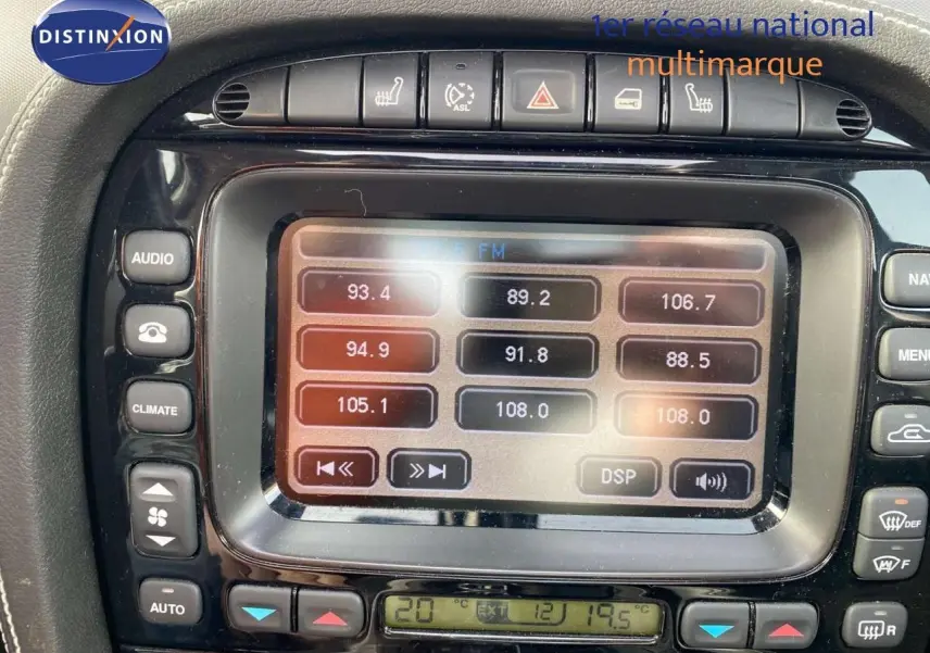 Gros plan sur l’écran central et les commandes de la Jaguar XJ6 noire de 2006, mettant en valeur la radio et la climatisation.