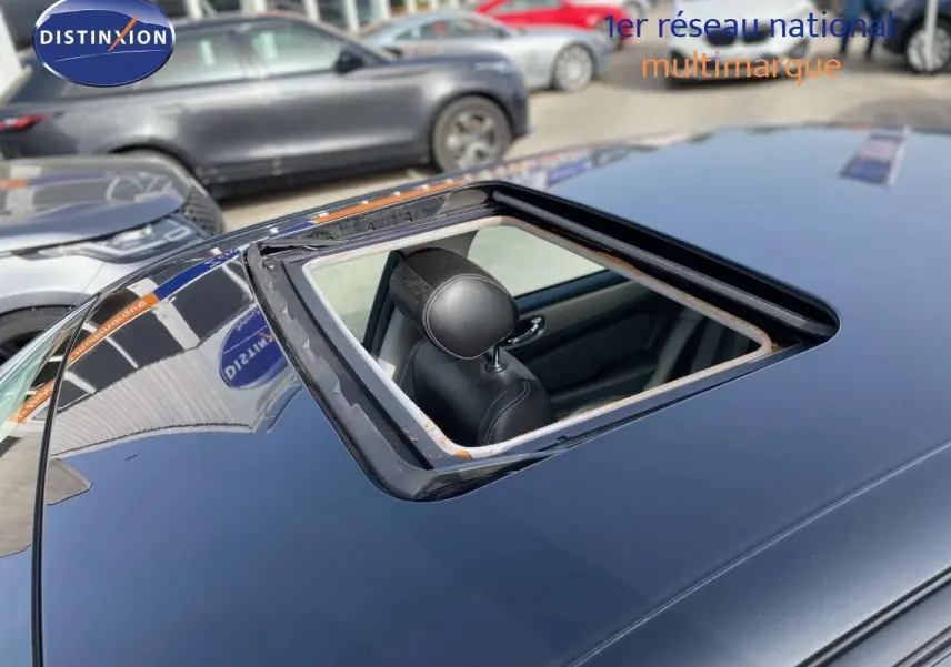 Toit ouvrant ouvert vu en plongée sur une Jaguar XJ6 noire, intérieur cuir noir visible depuis l'extérieur.