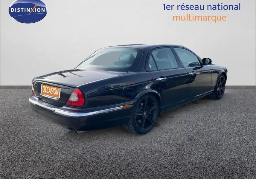 Jaguar XJ6 noir vue 3/4 arrière droit, soulignant ses jantes noires et sa silhouette élégante quatre portes.