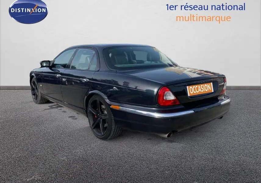 Jaguar XJ6 noir vue 3/4 arrière gauche, berline élégante avec jantes noires et feux arrière rouges.